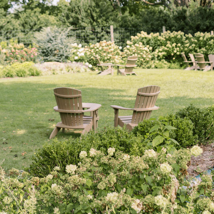 Two brown lawn chairs in a garden space at Fleetwood Farm Winery, a Virginia winery with outdoor seating.