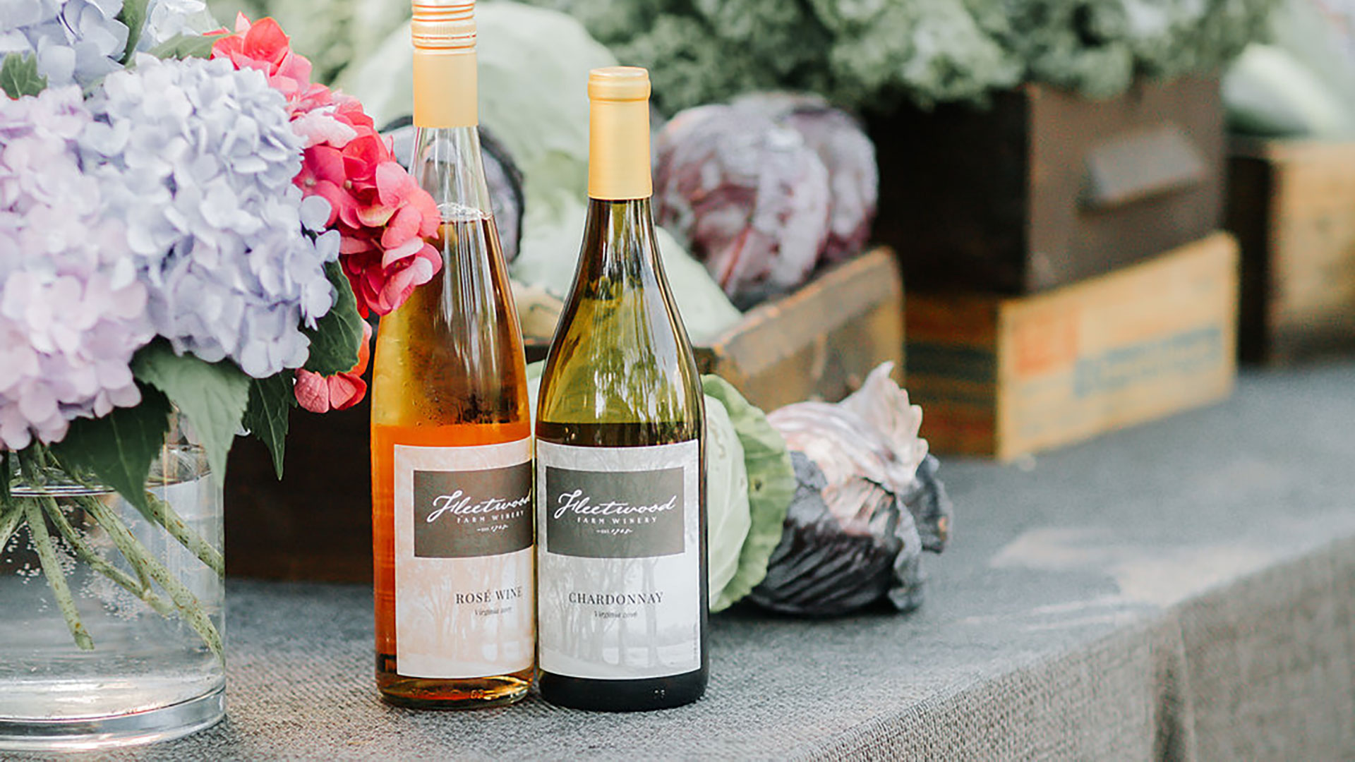 A bottle of Rosé & Chardonnay rested on a table with purple flowers at an outdoor winery in Leesburg, Virginia.