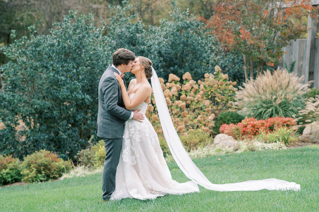 A bride and groom kissing in a field at a Virginia winery and farm wedding venue in Leesburg.