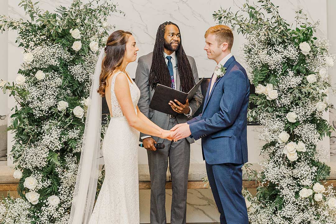 A groom and bride at the altar, holding hands during their wedding ceremony at a garden wedding venue in Northern Virginia.