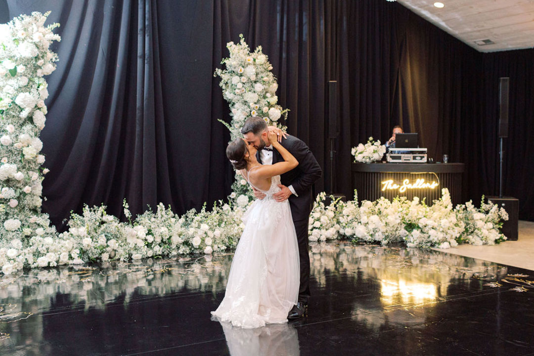 A bride and groom sharing a kiss on stage during their first dance at a wedding reception in Fleetwood Farm Winery, a winery wedding venue in Loudoun County, VA.