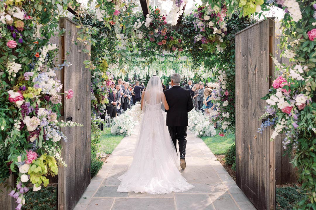 The bride walking with her father down the aisle in Fleetwood Farm Winery's outdoor garden wedding venue in Leesburg, VA.