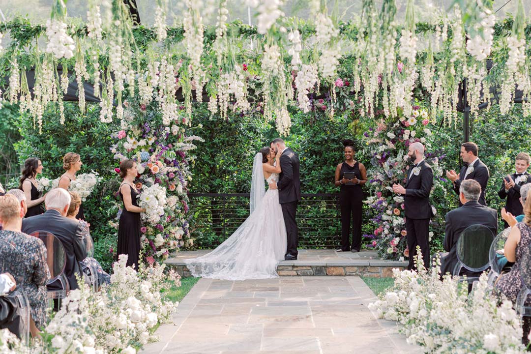 A bride and groom sharing a first kiss following a wedding ceremony in Fleetwood Farm Winery's outdoor wedding space