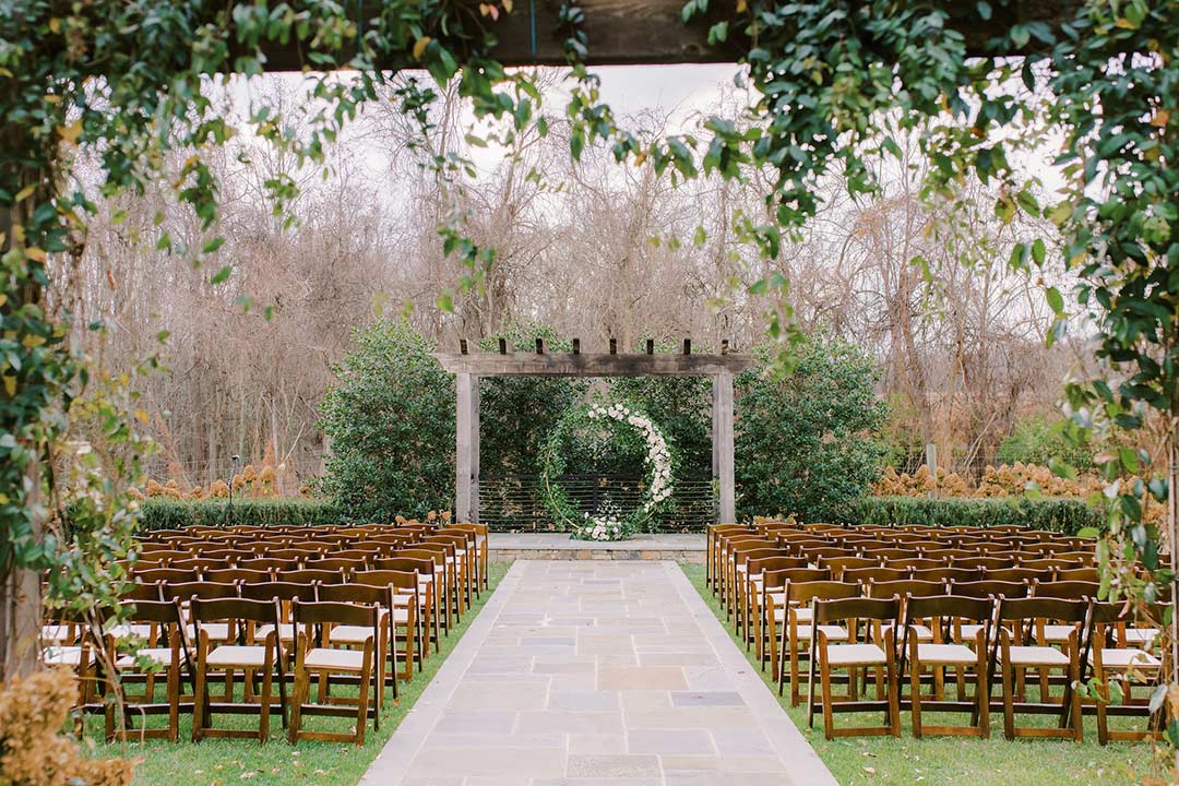 Rows of fold-up chairs prepared for an outdoor wedding ceremony in Fleetwood Farm Winery's ceremony garden.