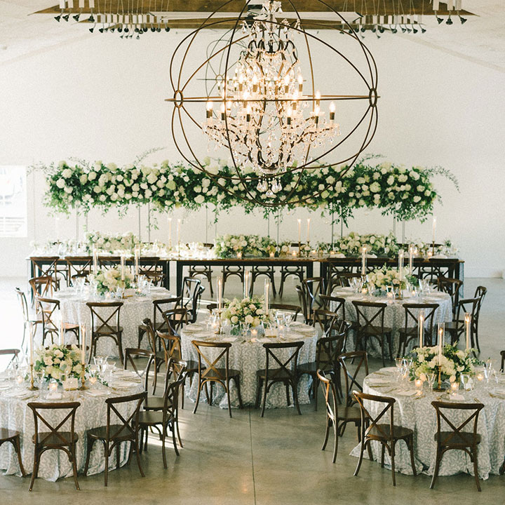 Set tables decorated with flower arrangements inside of a wedding reception venue in Loudoun County, Virginia.