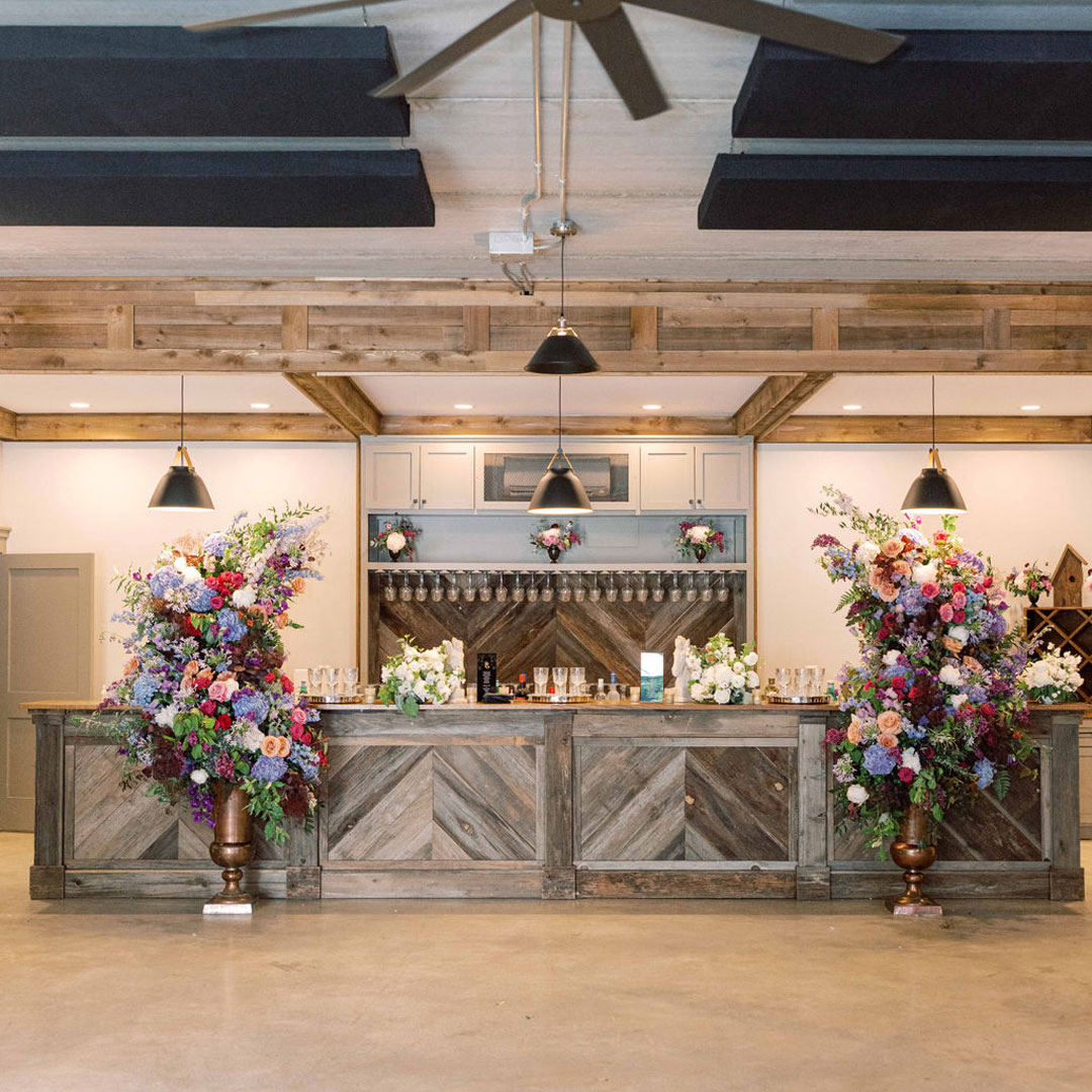 A bar and barrel room decorated with flowers at a winery wedding venue in Loudoun County, Virginia.