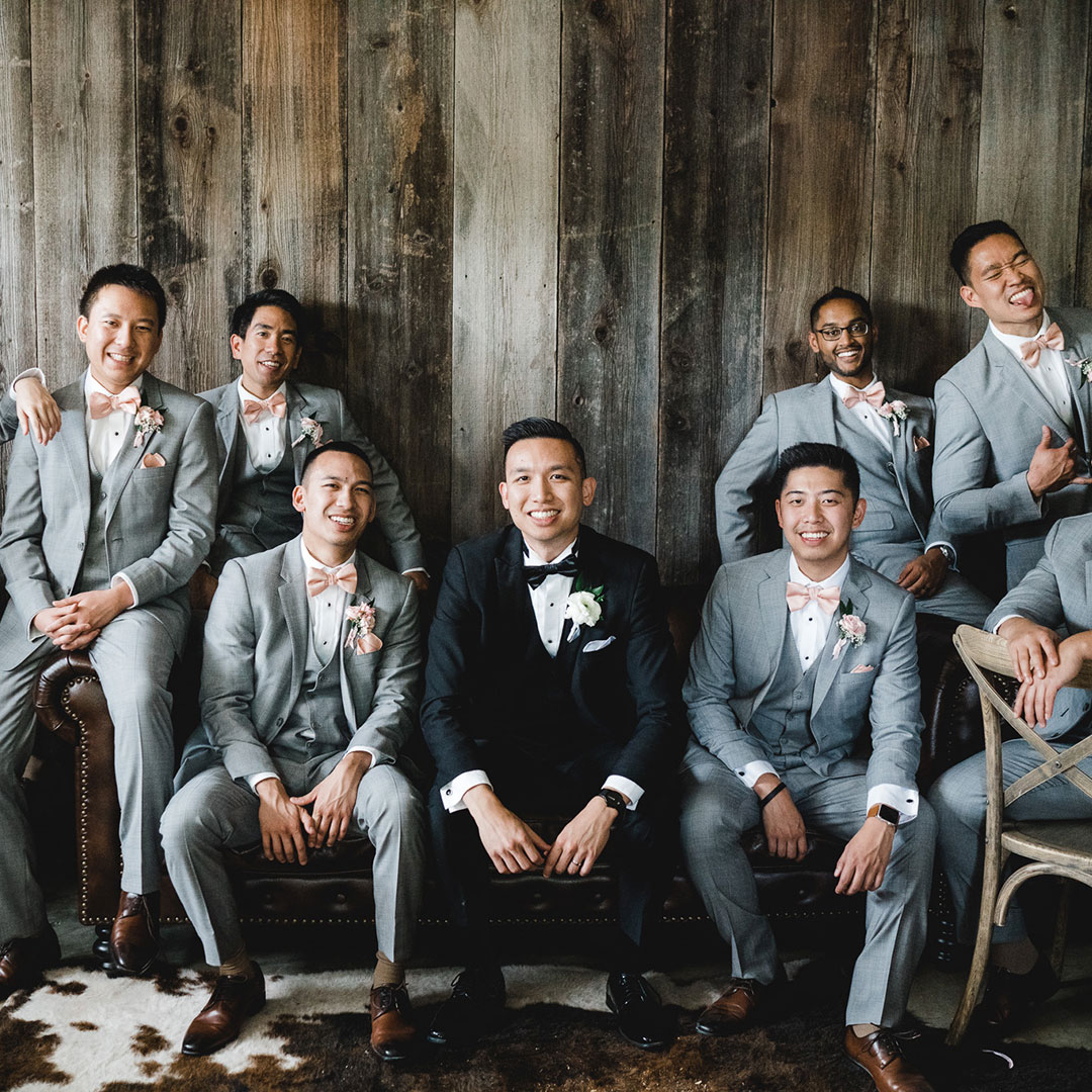 A groom seated, surrounded by his groomsmen in Fleetwood Farm Winery's groomsmen suite.