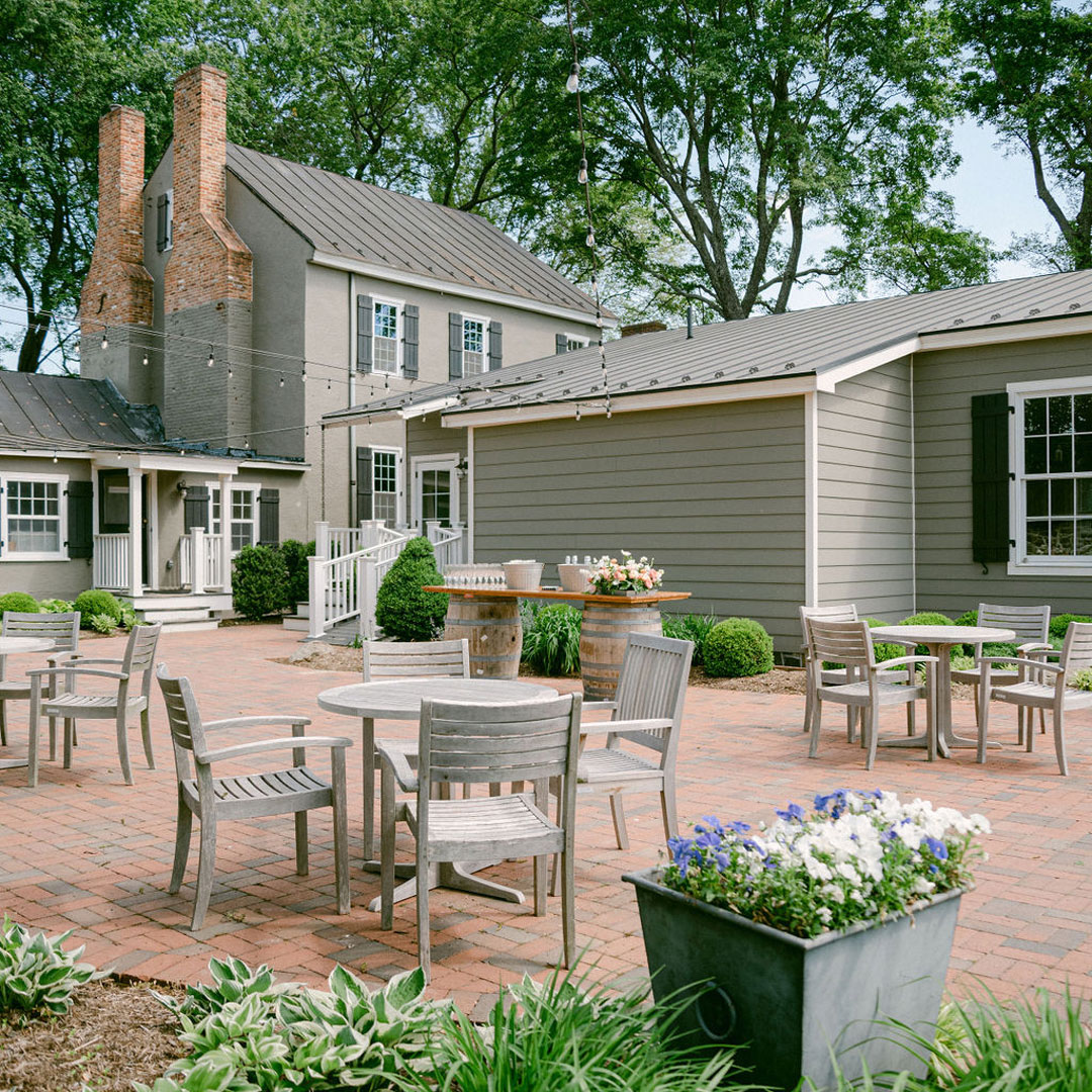 An outdoor patio area with flowers and wooden tables that could be used as a private event space near me in Leesburg, Virginia.