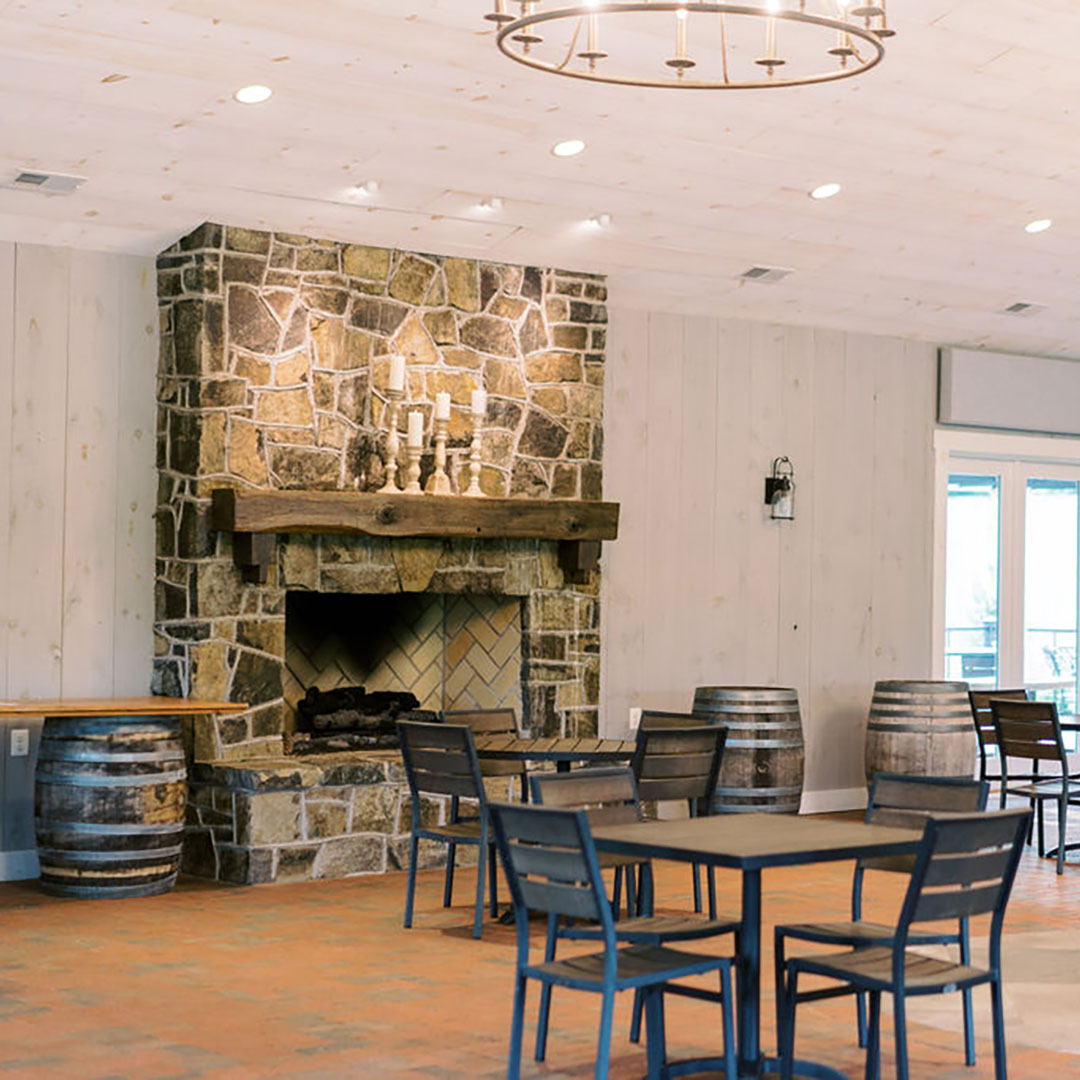 A stone fireplace and wooden tables in an indoor outdoor event space near me in Leesburg, Virginia.