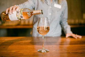 A close-up of a Fleetwood Farm Winery employee pouring a glass of wine.