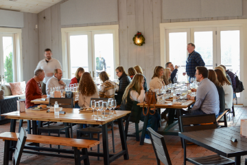 Group seated at a large wooden table inside of Fleetwood Farm Winery in Leesburg, Virginia.