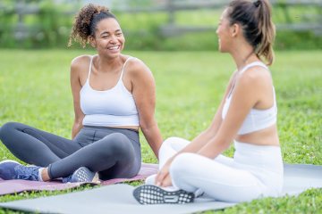 Two women seated on yoga mats in a field, representing winery events & classes available at Fleetwood Farm Winery in Leesburg, VA.